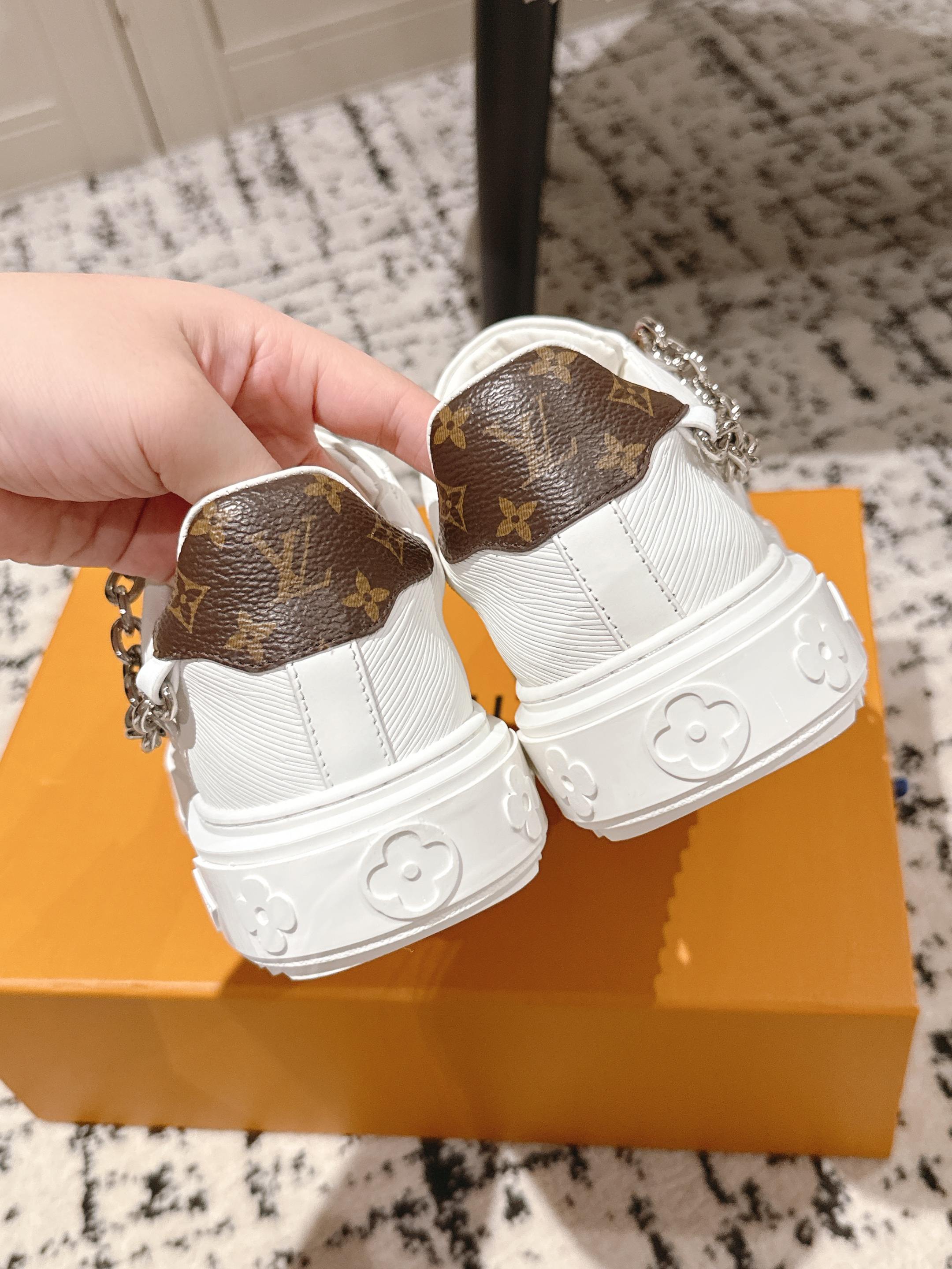 White Louis Vuitton sneakers with brown monogram heel tabs and silver chain detail