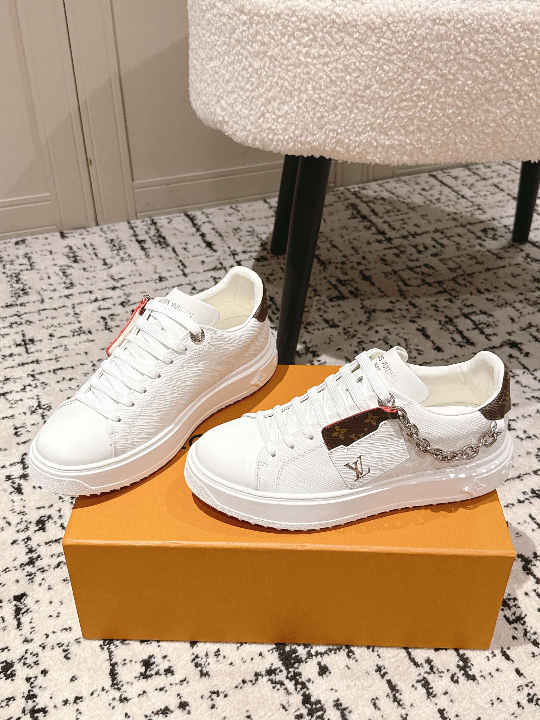 White Louis Vuitton sneakers with brown monogram side panel, lace-up front, chain