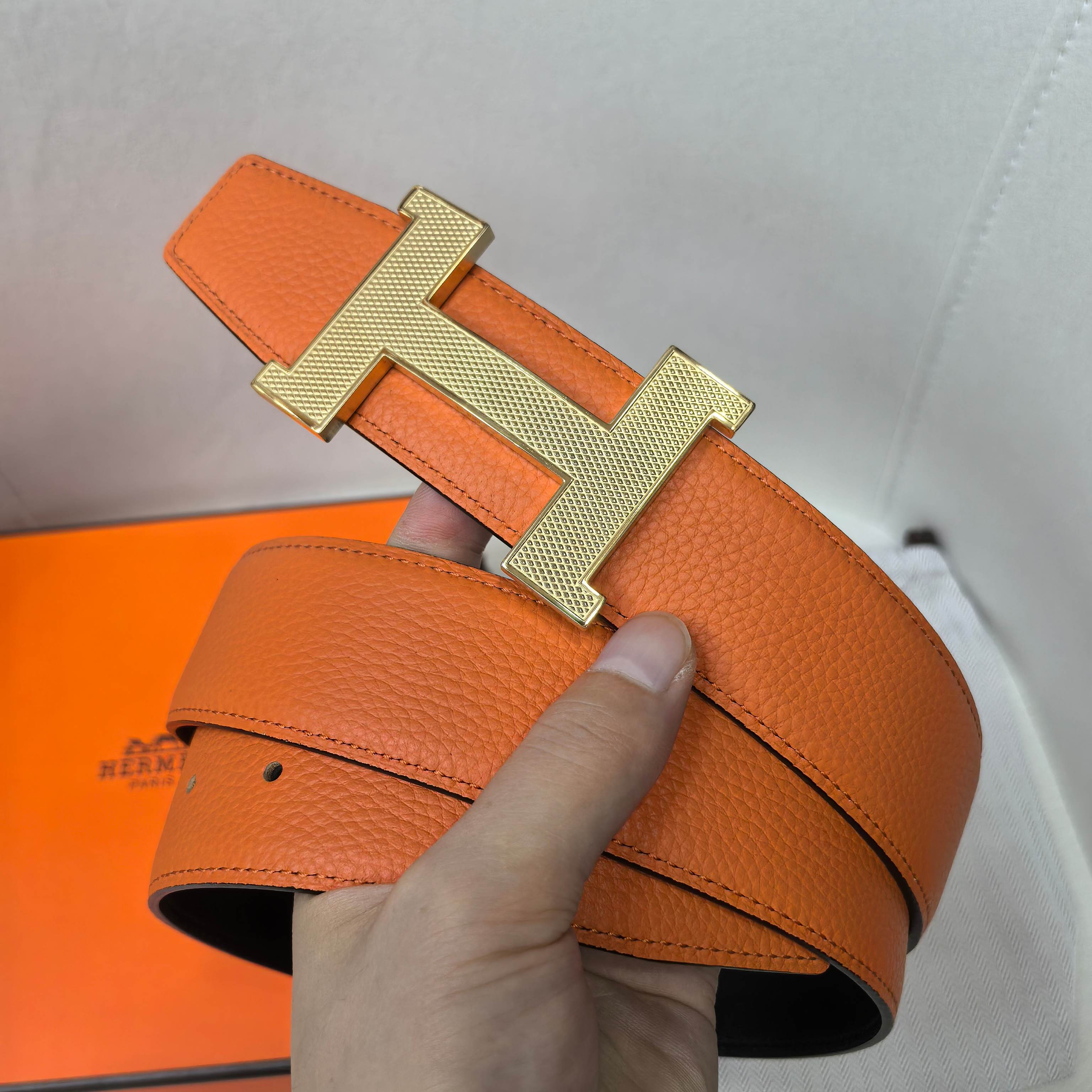 Orange leather belt with gold H buckle and adjustable strap holes