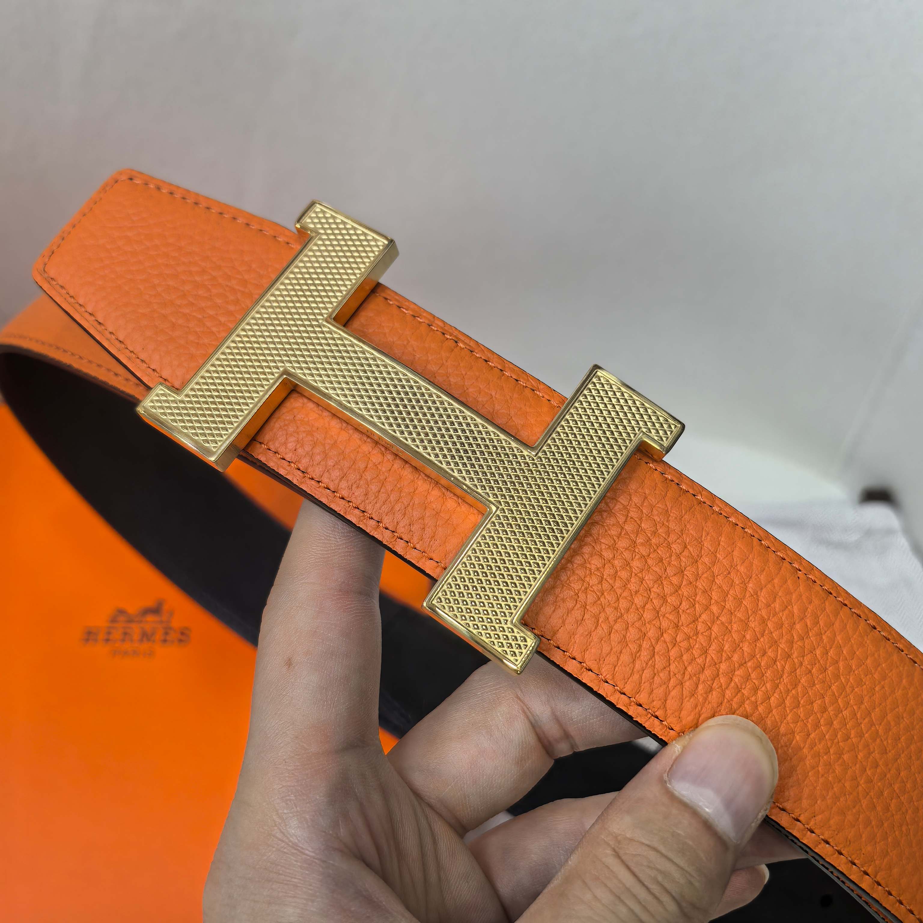 Orange leather belt with gold H buckle and structured leather keeper