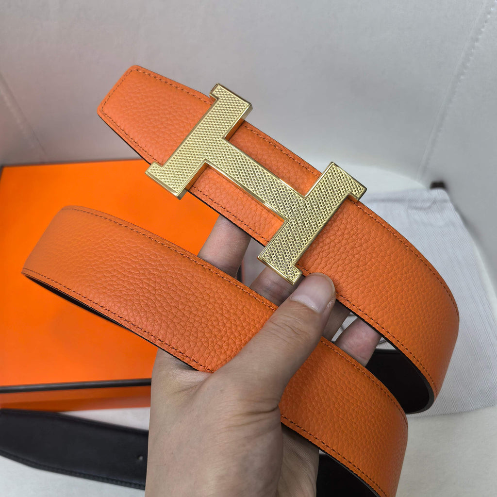Orange leather belt with gold H buckle and pin-hole strap detail