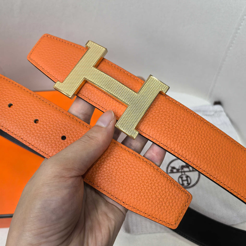 Orange leather belt with gold H buckle and textured strap with holes