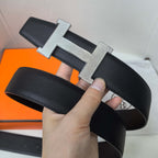 Leather belt with large silver H buckle and dark textured strap, close-up