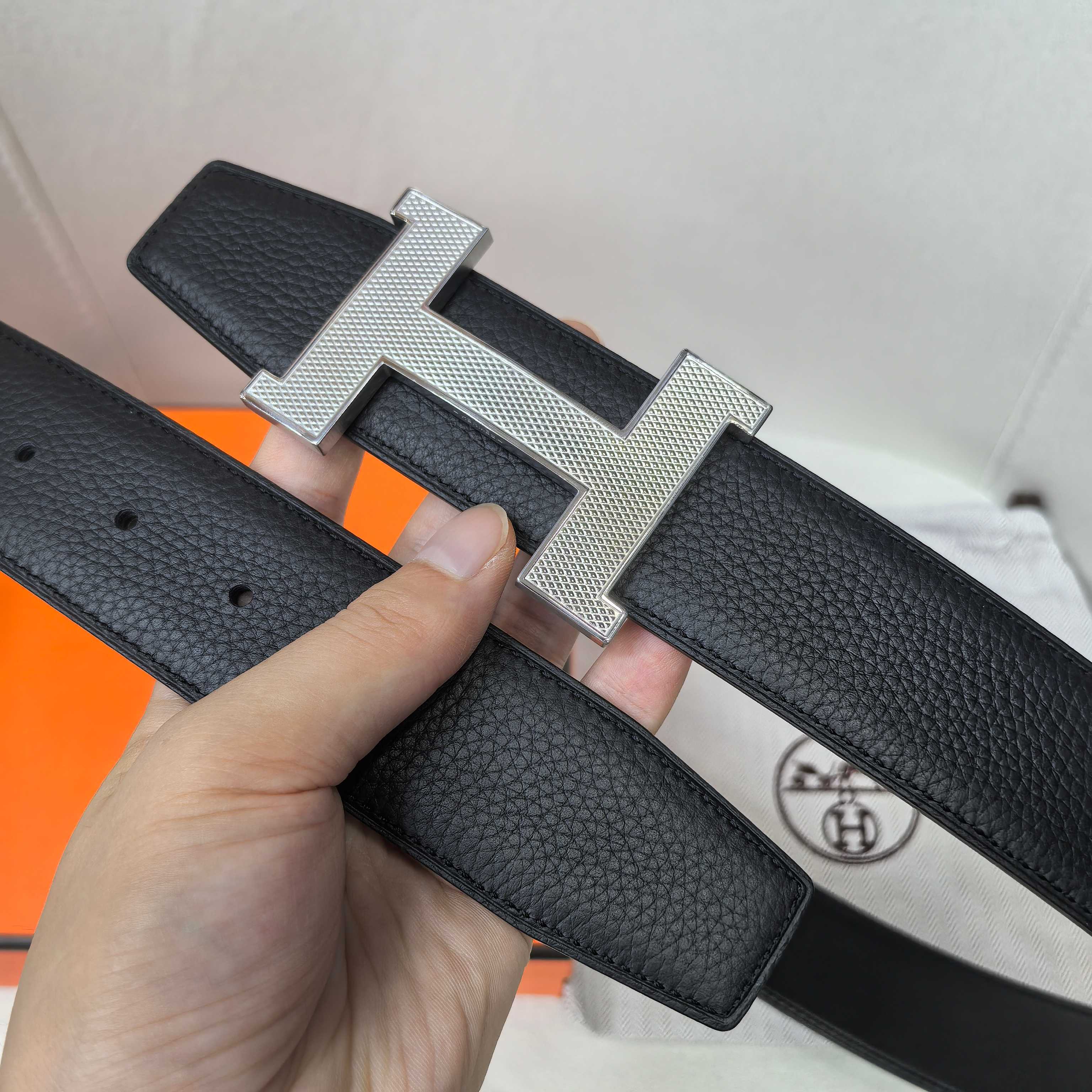 Leather belt with silver H buckle, dark textured strap, loop keeper visible