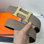 Gray leather belt with gold H buckle detail and perforated strap end