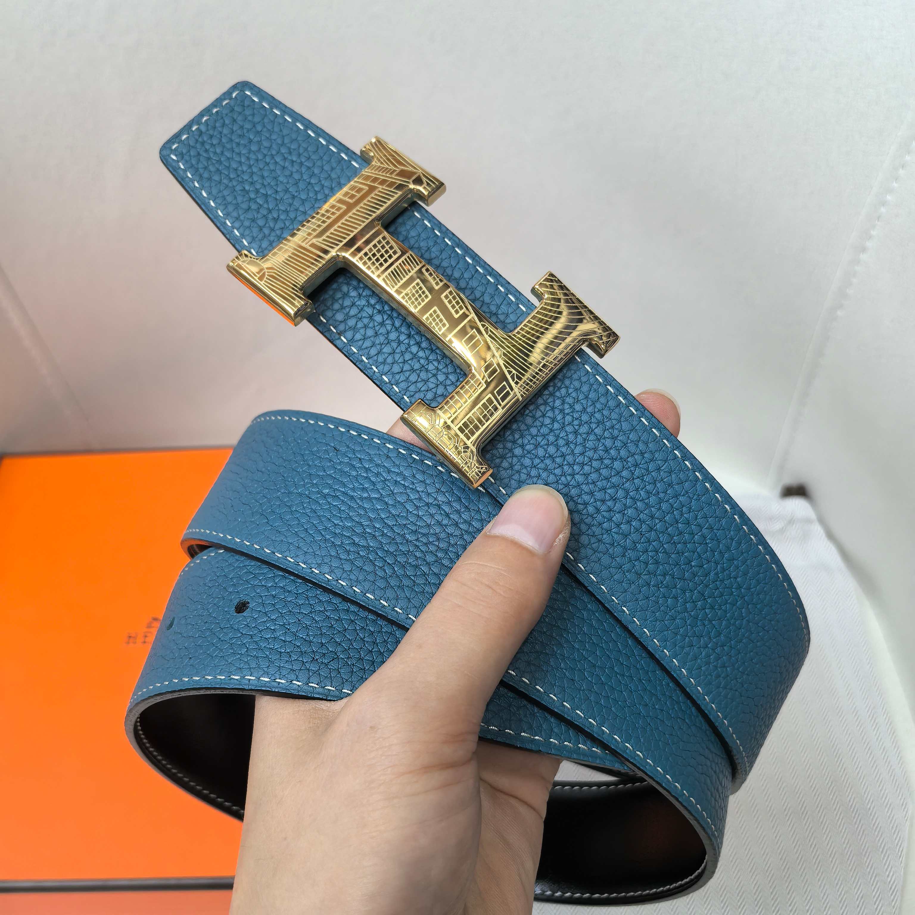Hermes belt in textured blue leather with gold-tone H buckle, strap end view