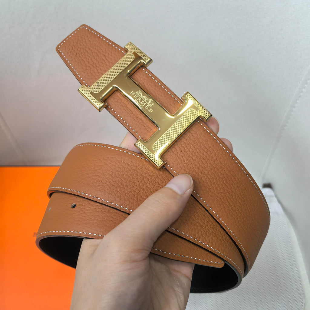 Hermes belt in tan leather with gold-tone double buckle and stitched strap edge.