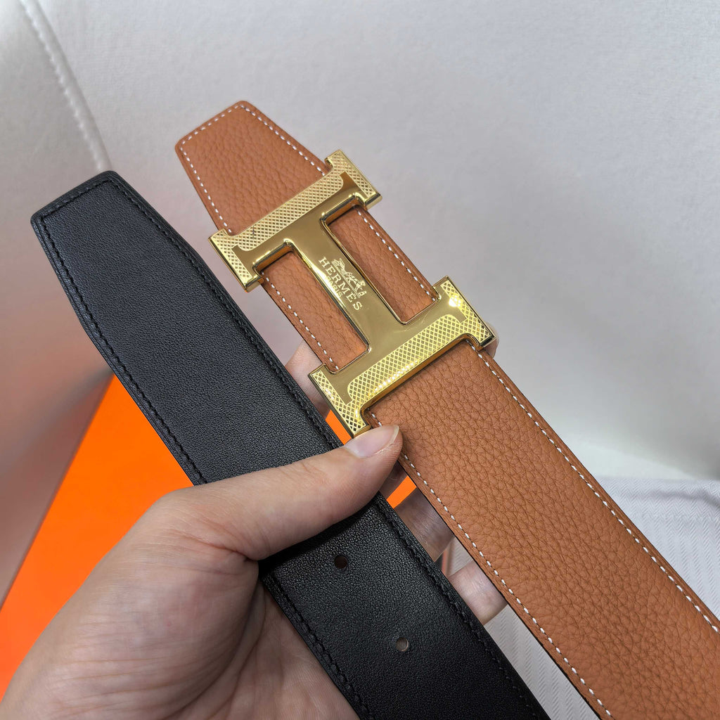 Hermes belt with tan and black leather straps and gold-tone buckle.