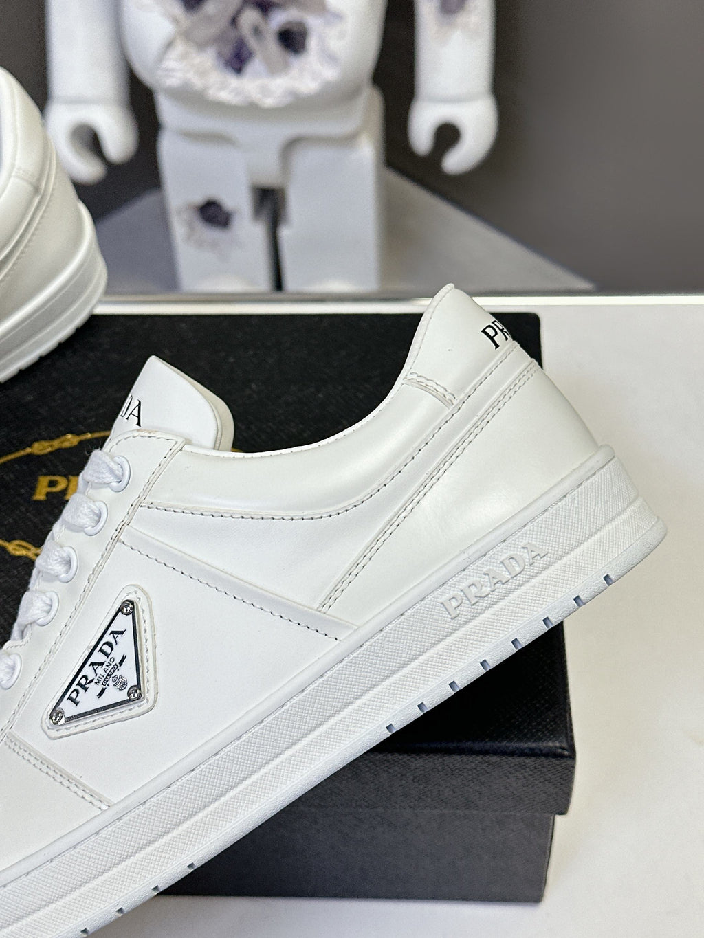 White low-top sneakers, quarter profile with PRADA logo on side