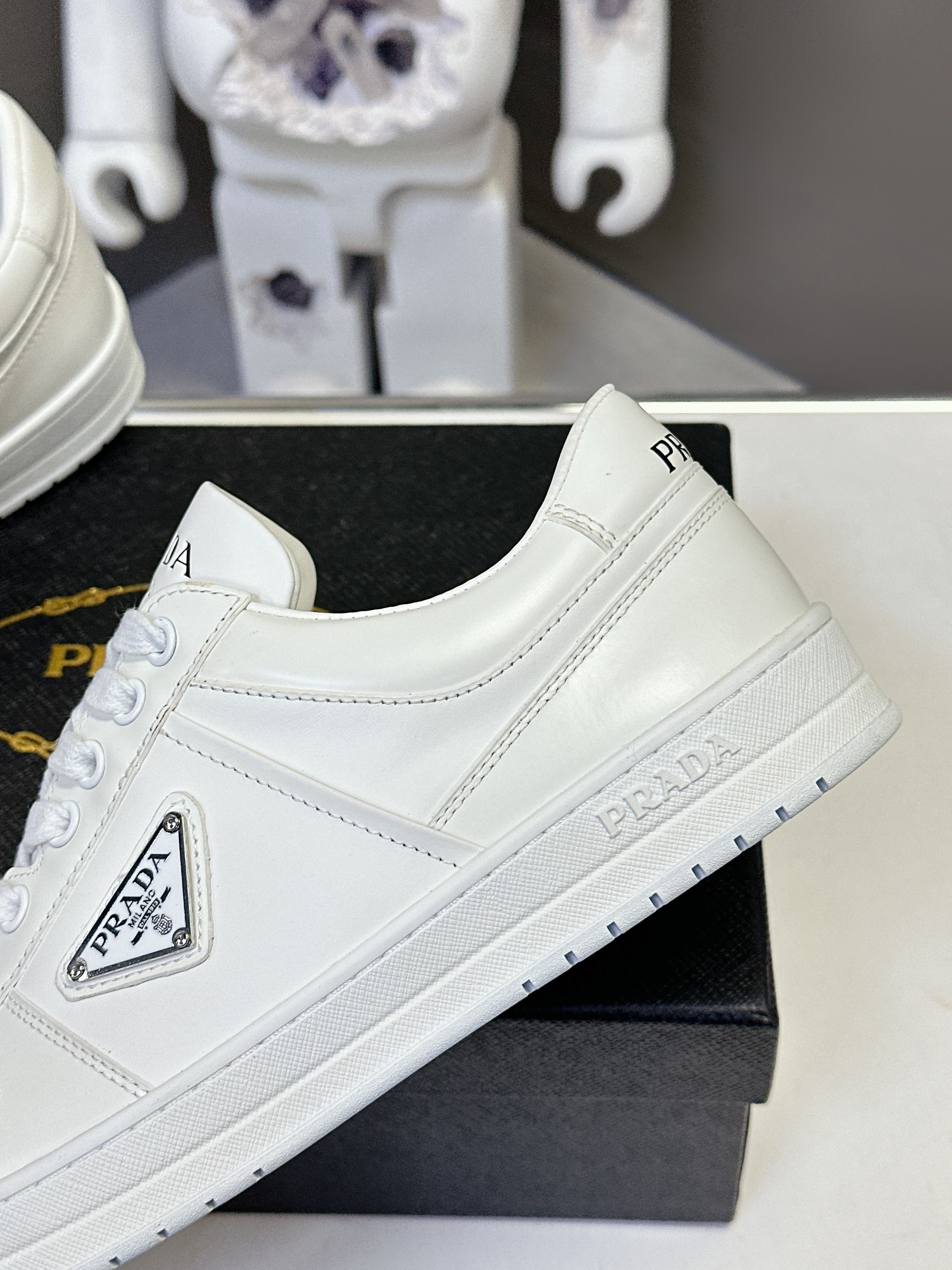 White low-top sneakers, quarter profile with PRADA logo on side