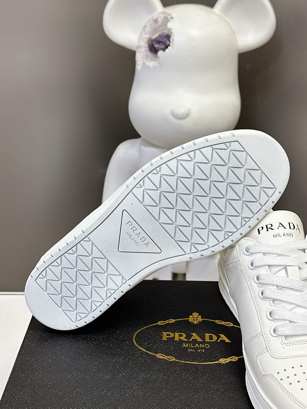 White Prada sneakers showing the tread outsole with textured pattern and logo.