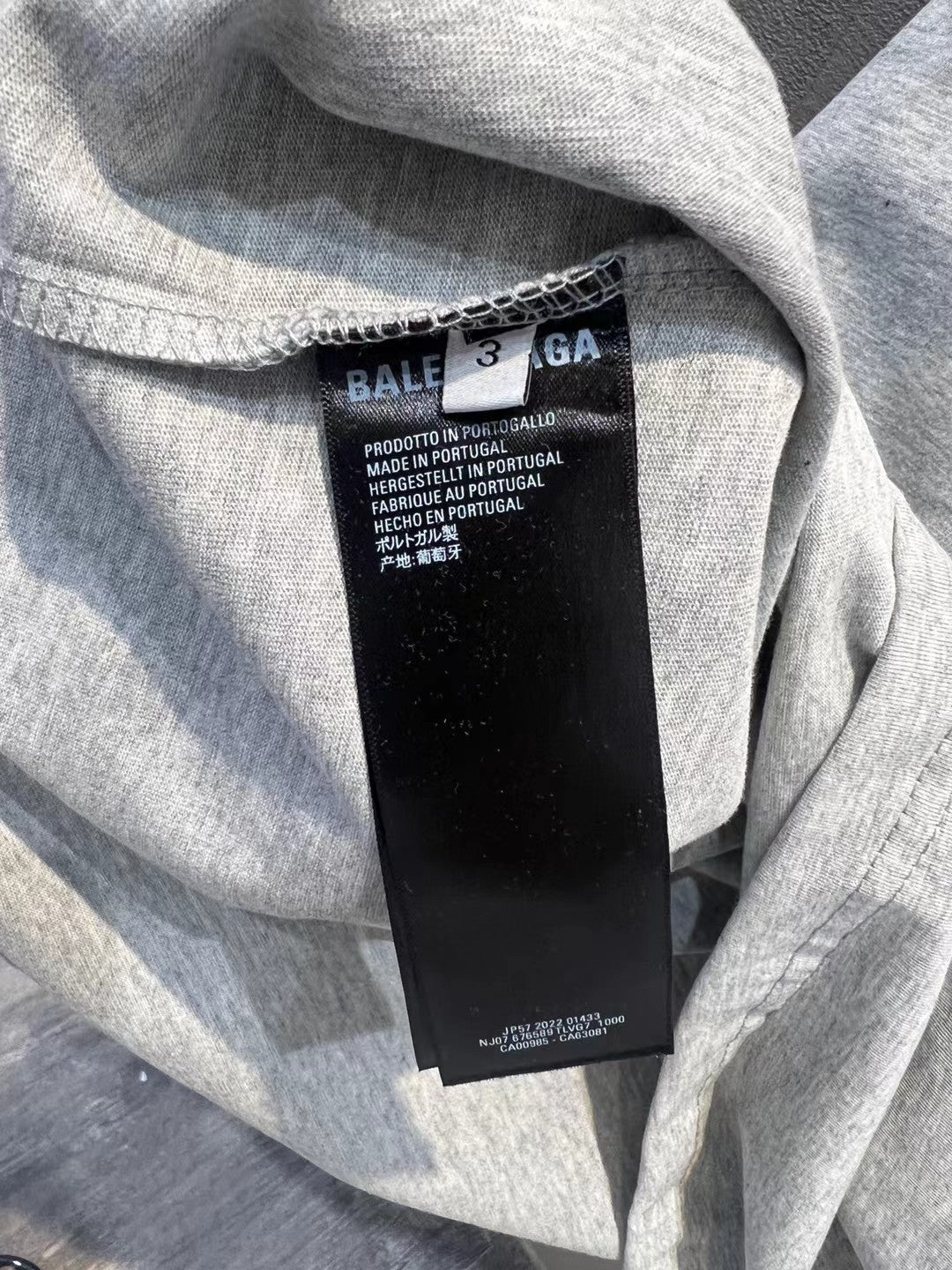 Light gray crewneck T-shirt with black inner neck label and small red logo text