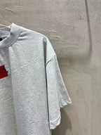 Light gray short-sleeve T-shirt with crewneck and red logo patch (side view)