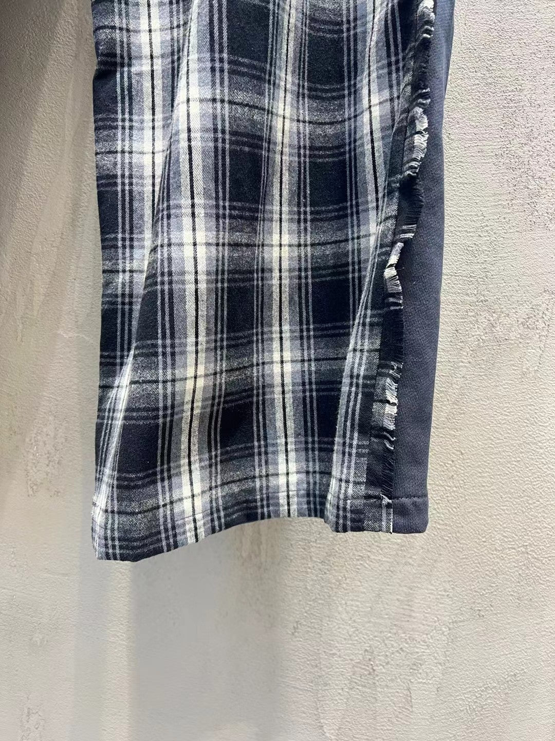 Plaid pants hem detail with stitched edge and textured elastic side trim