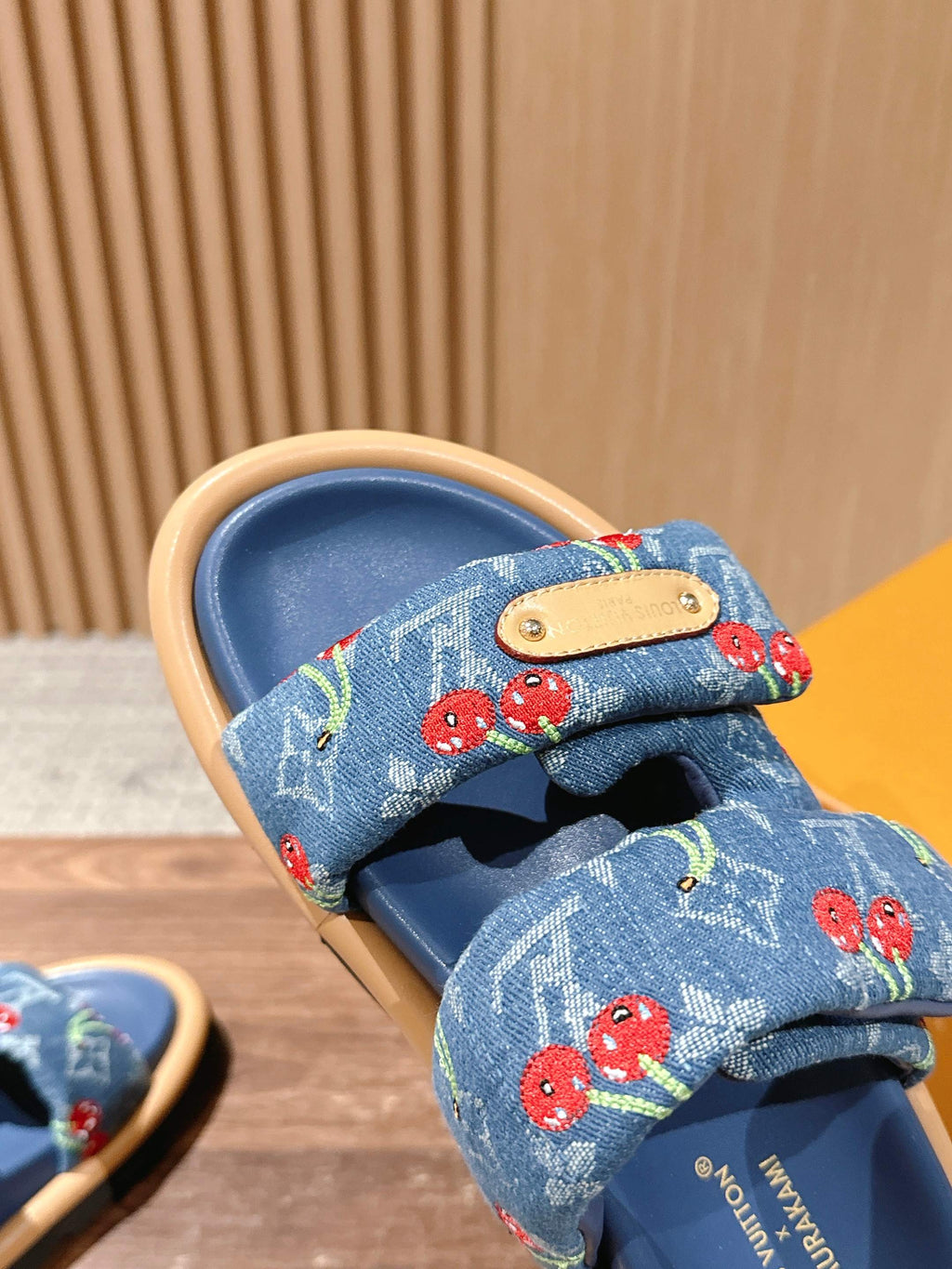 Louis Vuitton blue denim sandal close-up, tan leather patch and cherry strap