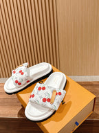 White cherry-pattern slide sandals with tan pull tab on the front strap