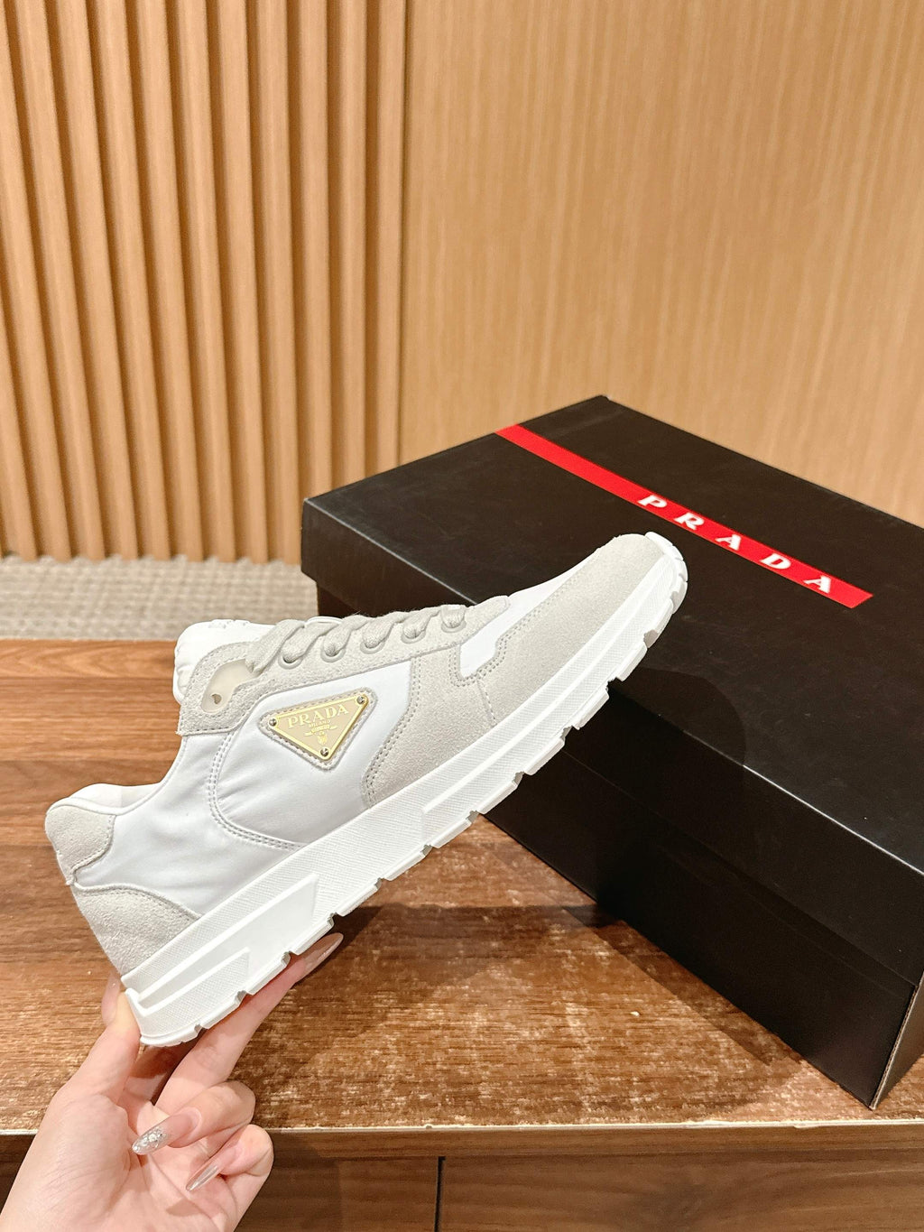 Prada unisex white sneakers, held by hand with side triangle logo patch