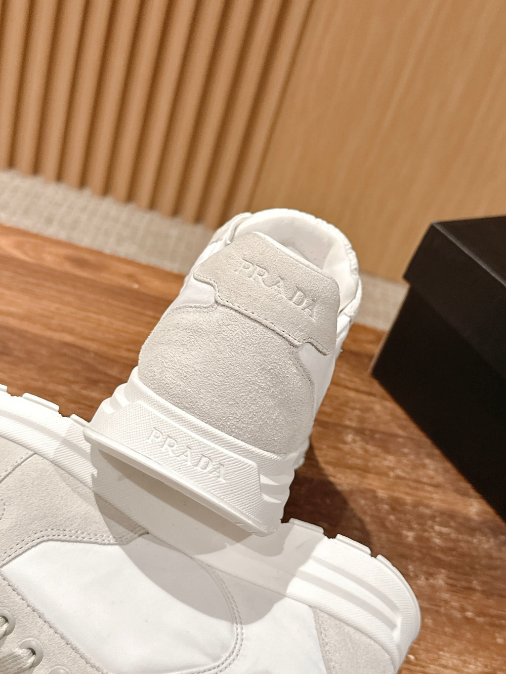 Prada unisex white sneakers rear view, logo on heel and pull-tab