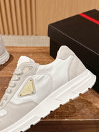 Prada unisex white sneakers close-up, side panel with gold triangle logo