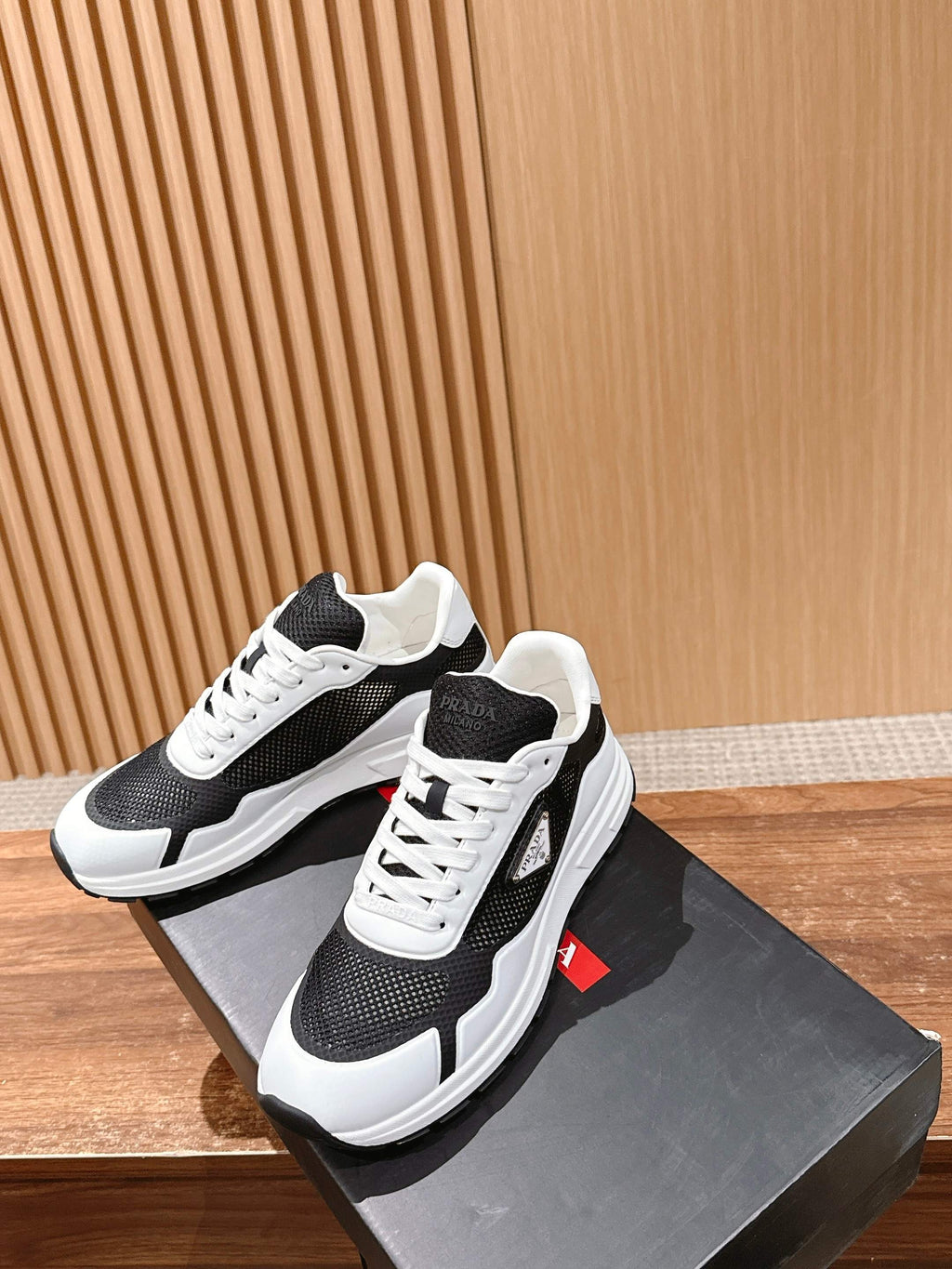Black and white unisex sneakers with perforated side panels and white laces