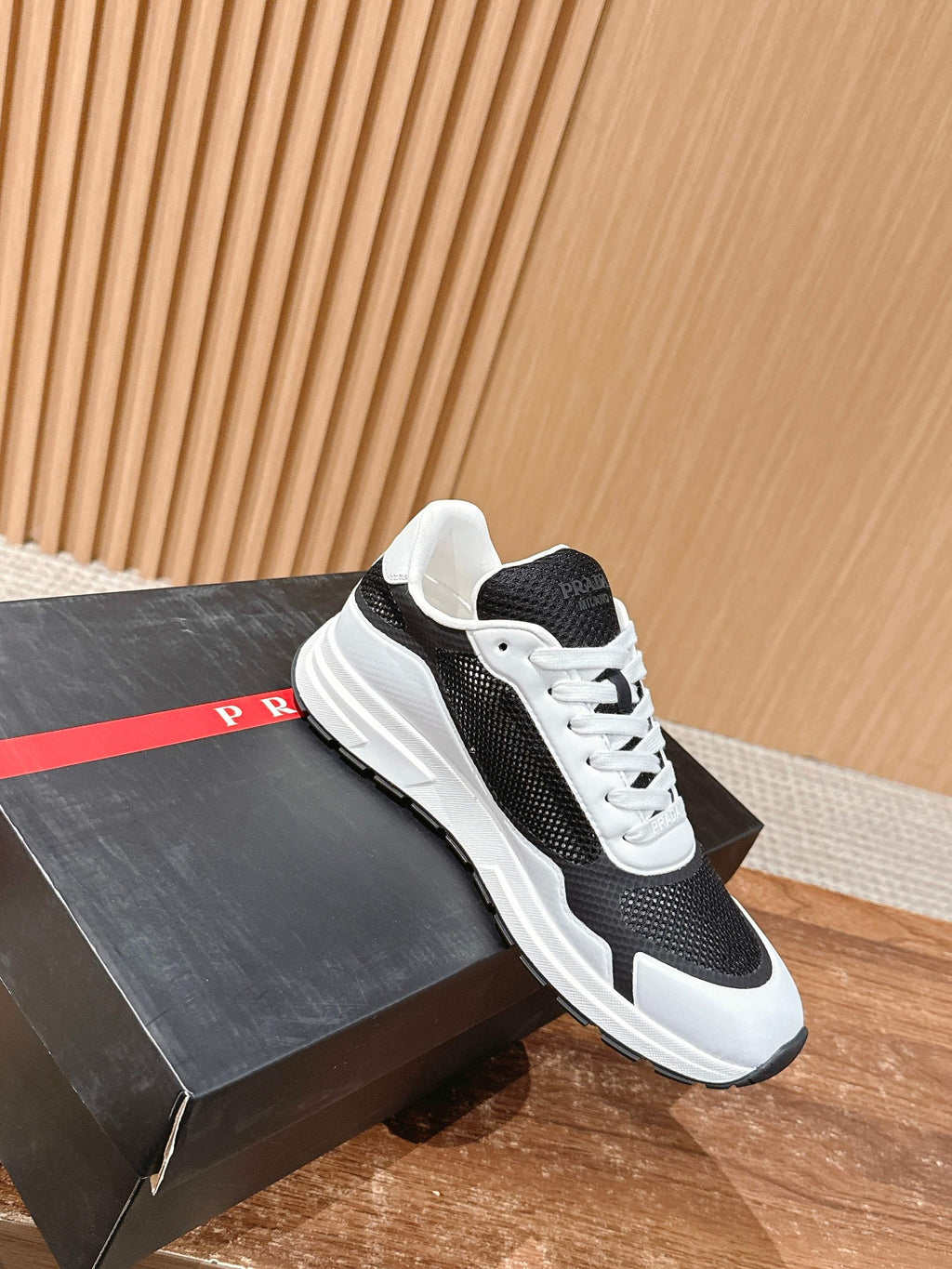Black and white unisex lace-up sneakers on display box with white rubber sole