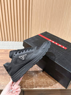Black lace-up sneakers shown in hand, mesh upper and rubber tread sole