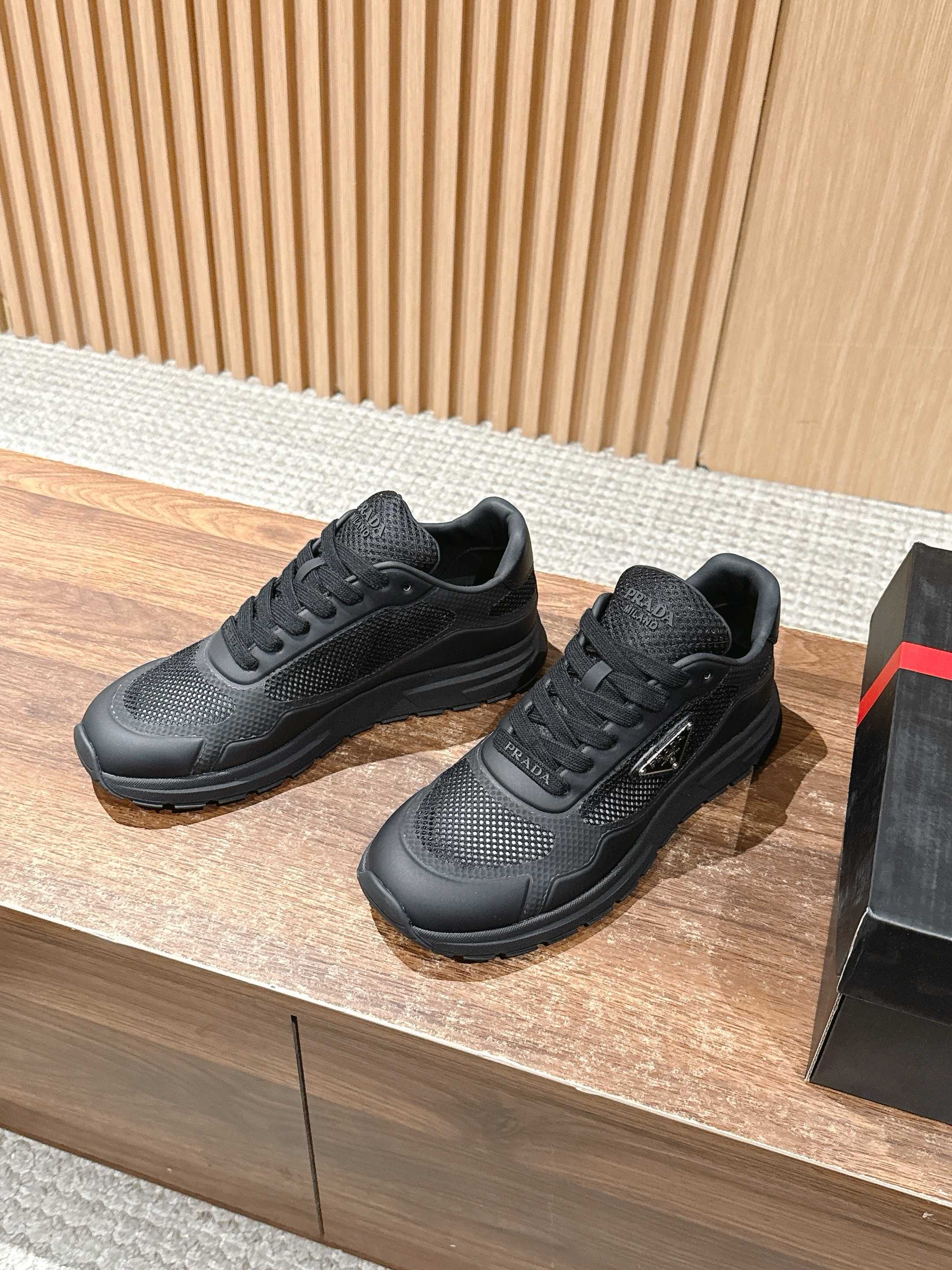 Black lace-up sneakers on box, mesh panels and chunky rubber sole visible