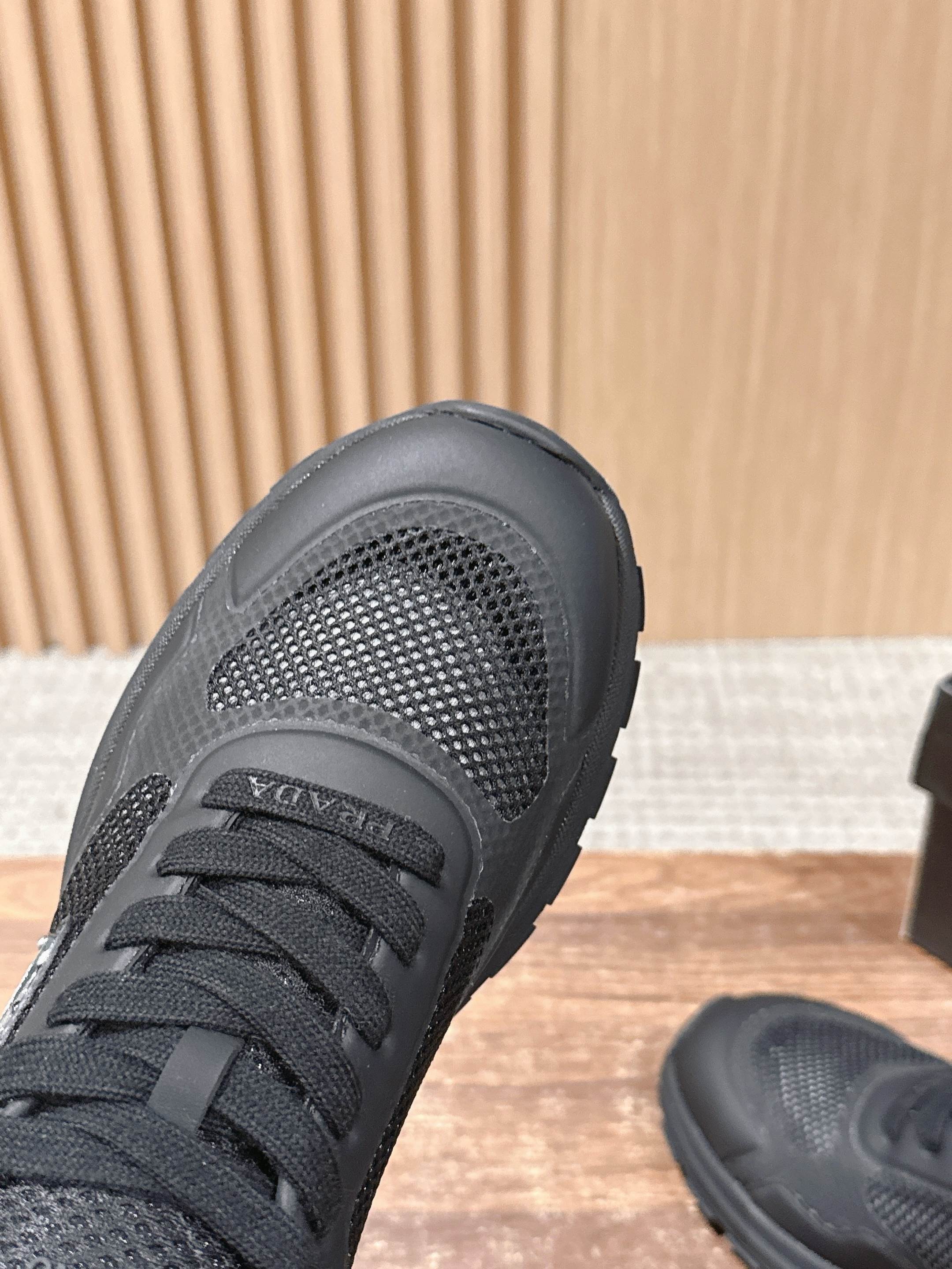 Black sneaker with mesh toe panel and lace-up front, close-up view