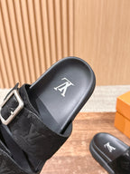 Close-up of black monogram slide sandal with silver buckle strap and logo footbed