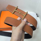 Brown leather belt with gold-tone buckle and keeper end, held in hand