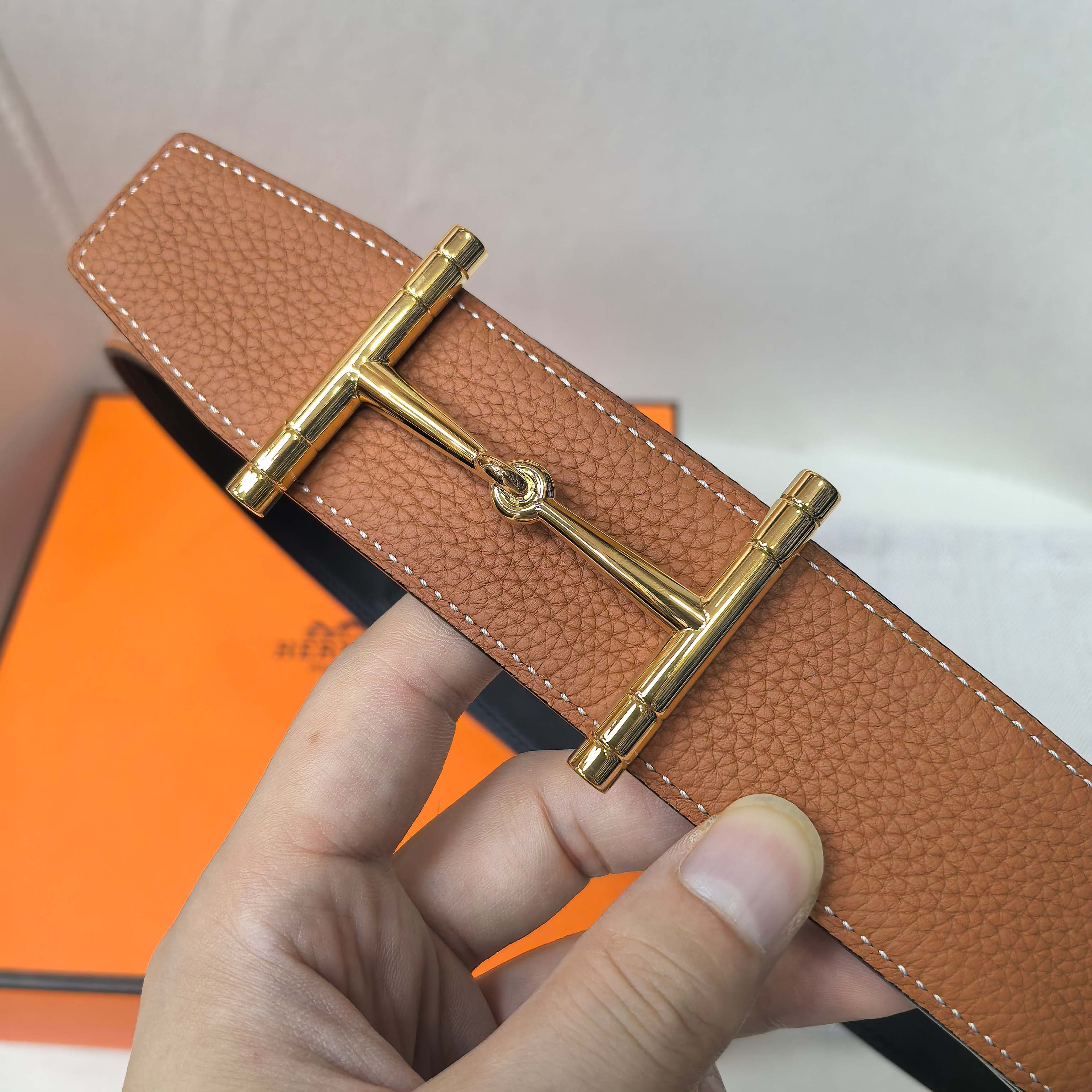 Brown leather belt with gold-tone buckle clasp and stitched leather edge