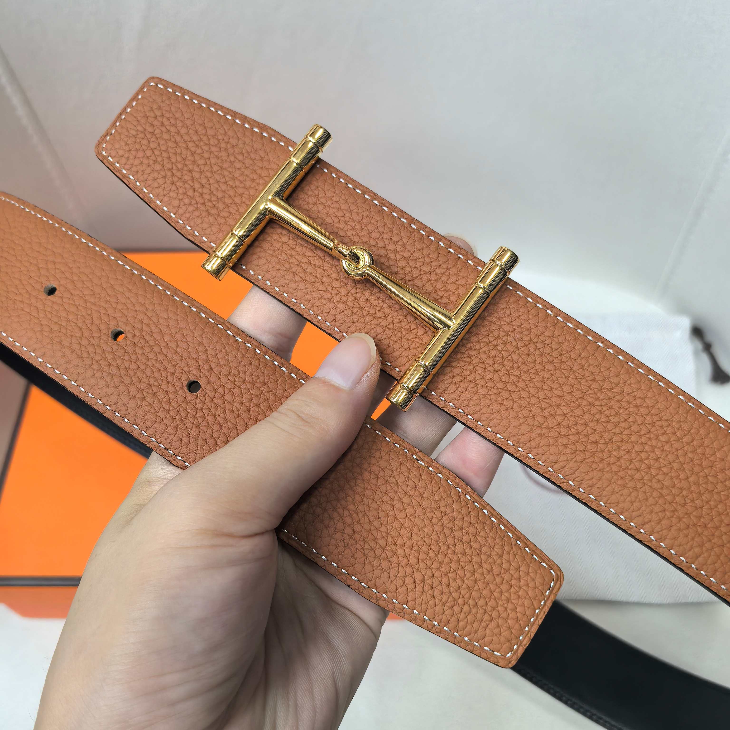 Brown leather belt close-up of gold buckle hardware and adjustment holes