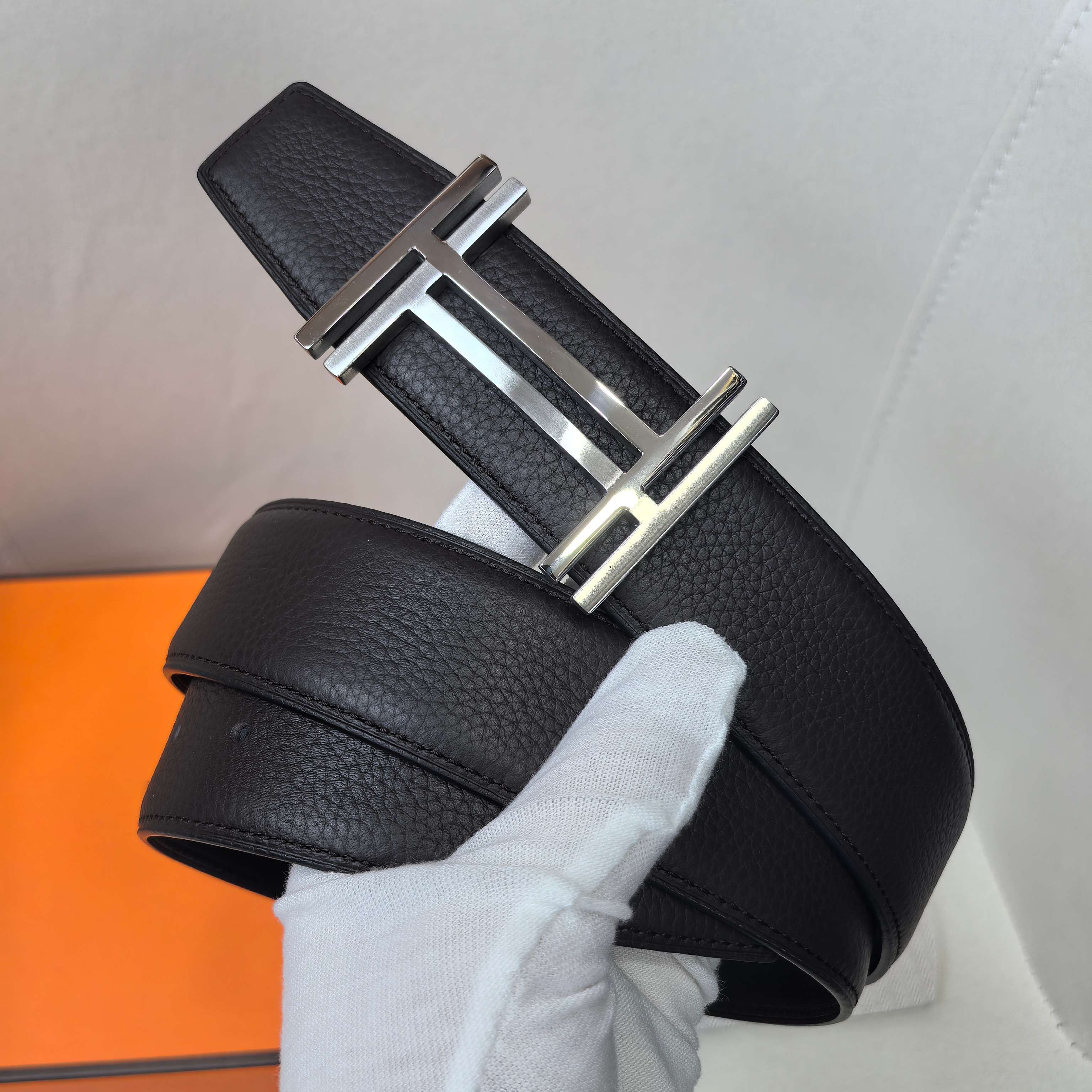 Leather belt with textured black leather and silver-tone metal buckle, close-up