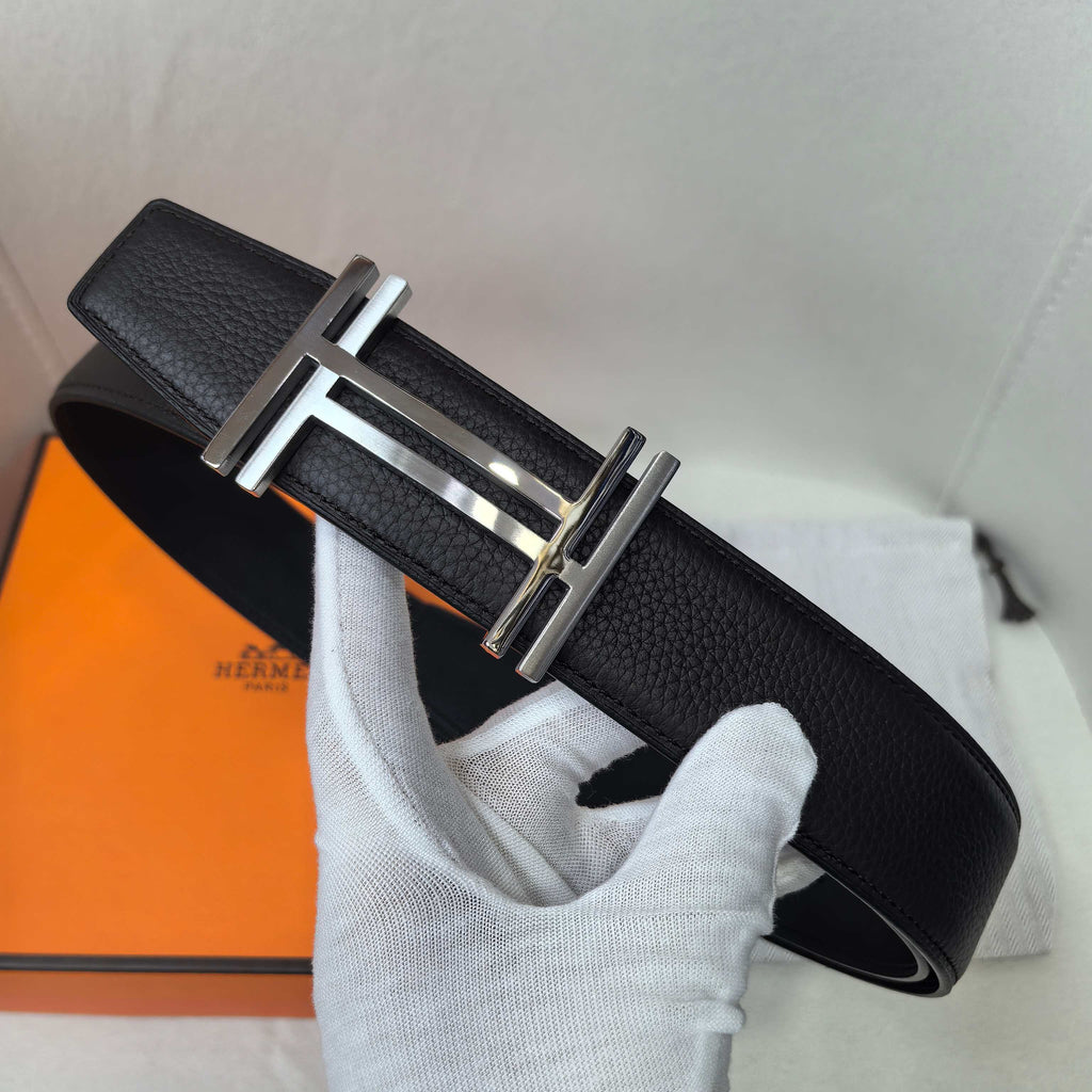 Leather belt with textured black leather and silver-tone buckle, belt tip visible