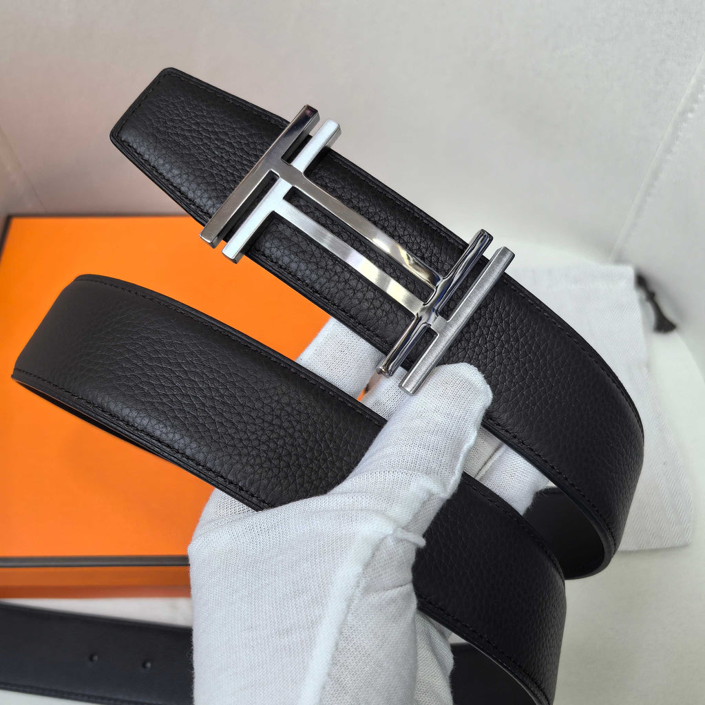 Leather belt with textured black strap and silver-tone buckle, angled view