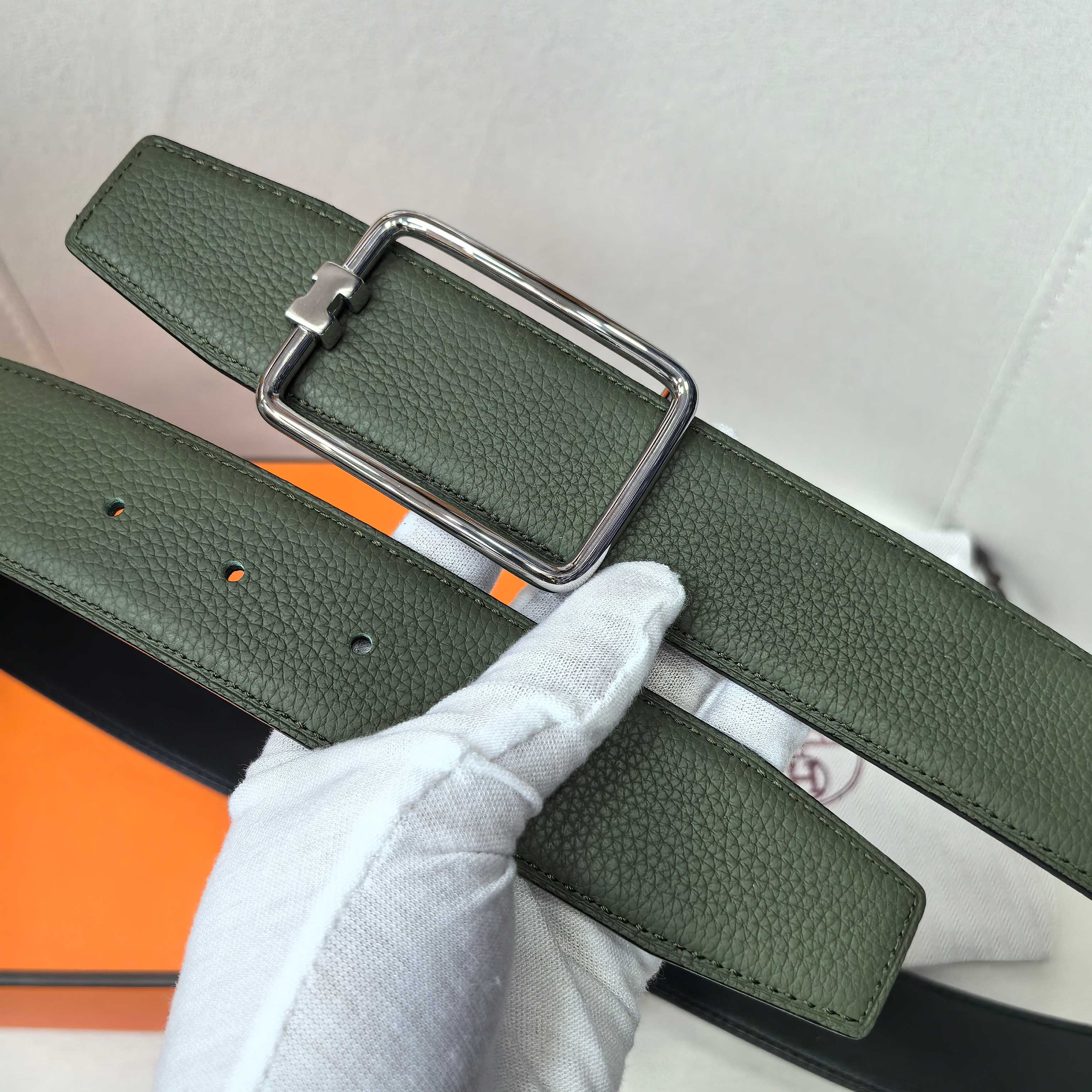Green leather belt with silver rectangular buckle and punched holes