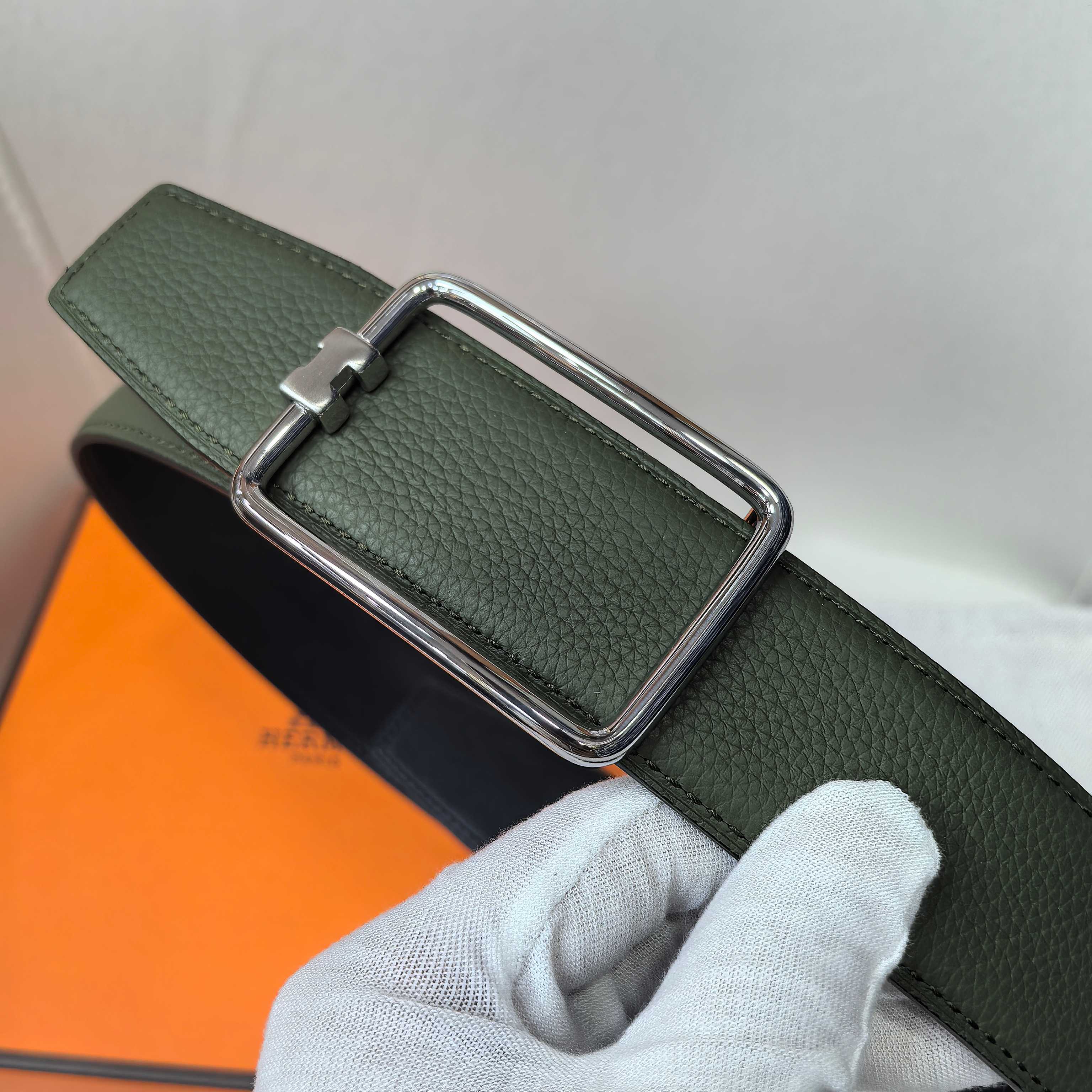 Green leather belt with silver rectangular buckle close-up
