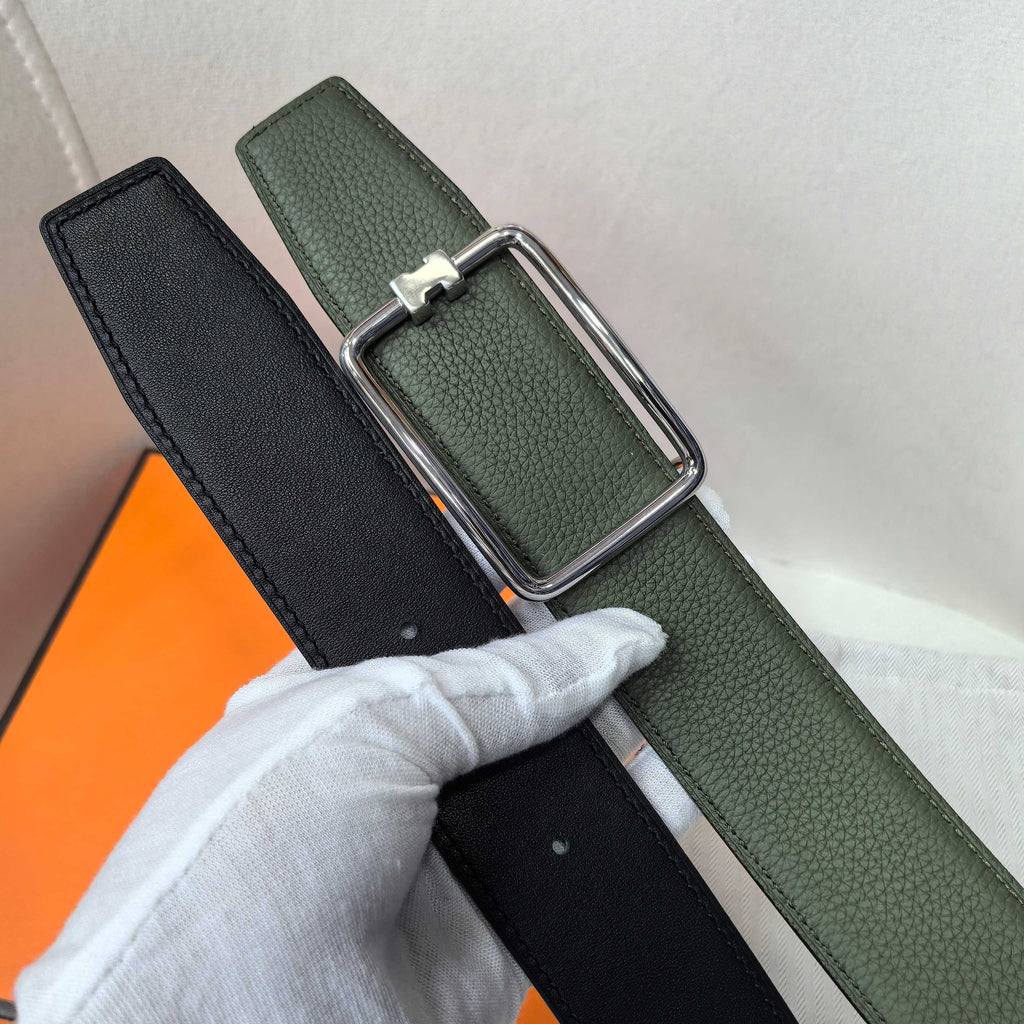 Green leather belt over black strap with silver rectangular buckle