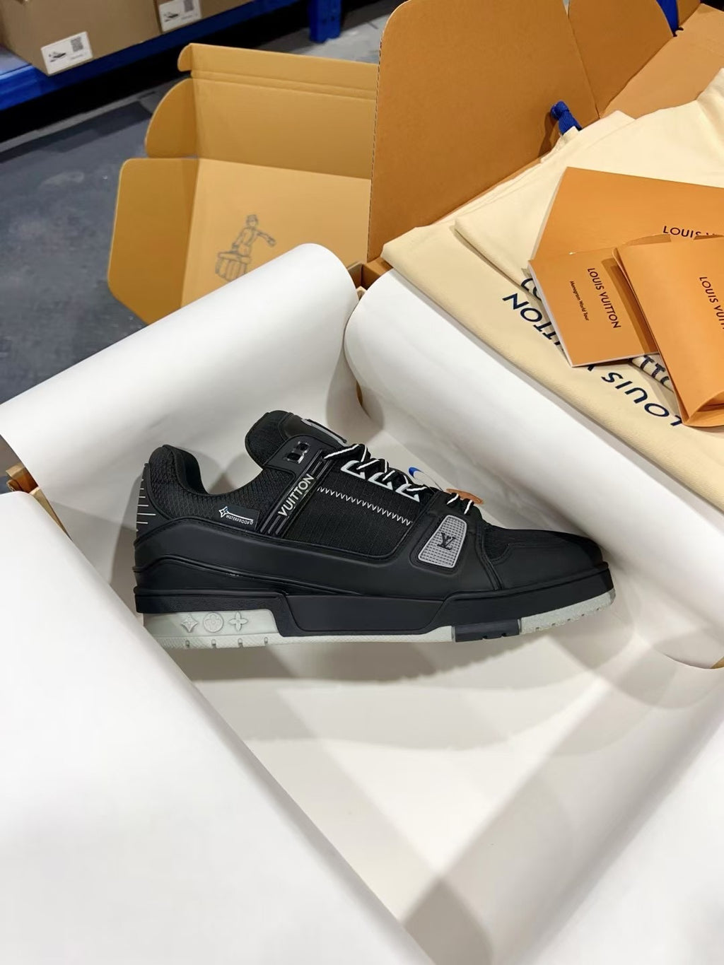 Black Louis Vuitton trainer shoes on white tissue, side profile