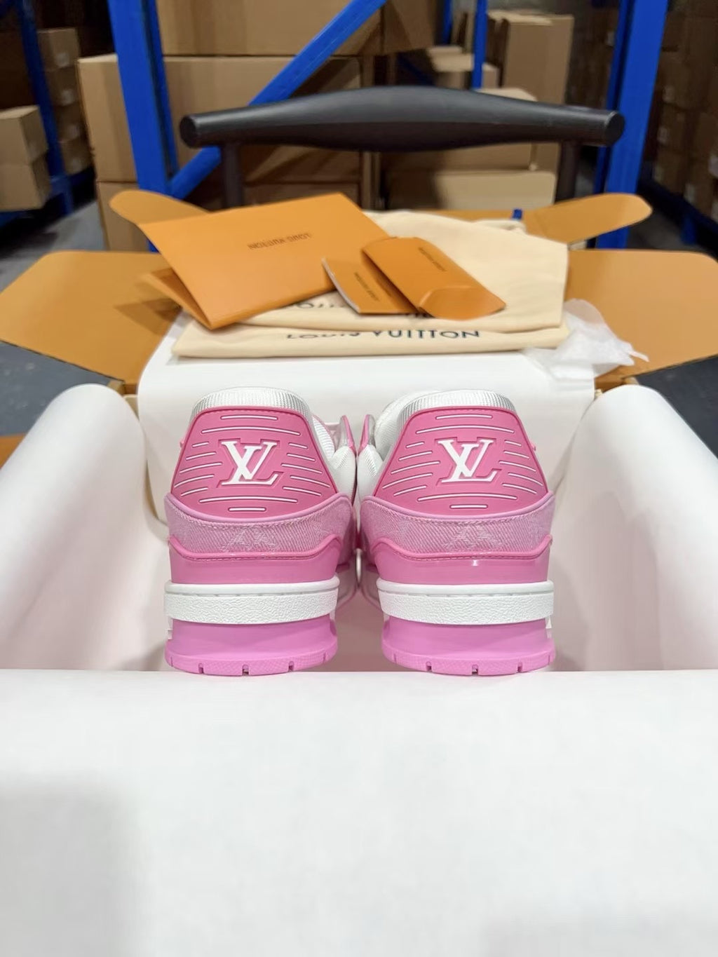 Pink and white sneakers showing heel backs with logo emblems
