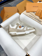 White Louis Vuitton trainer sneaker with LV emblem on side, lace-up, close side angle.