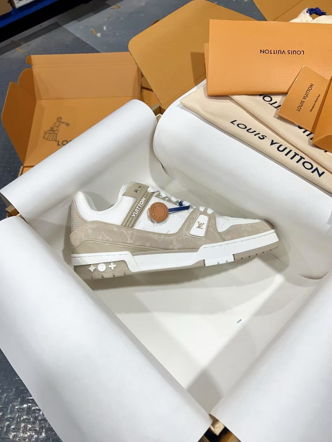 White Louis Vuitton trainer sneaker with LV emblem on side, lace-up, close side angle.