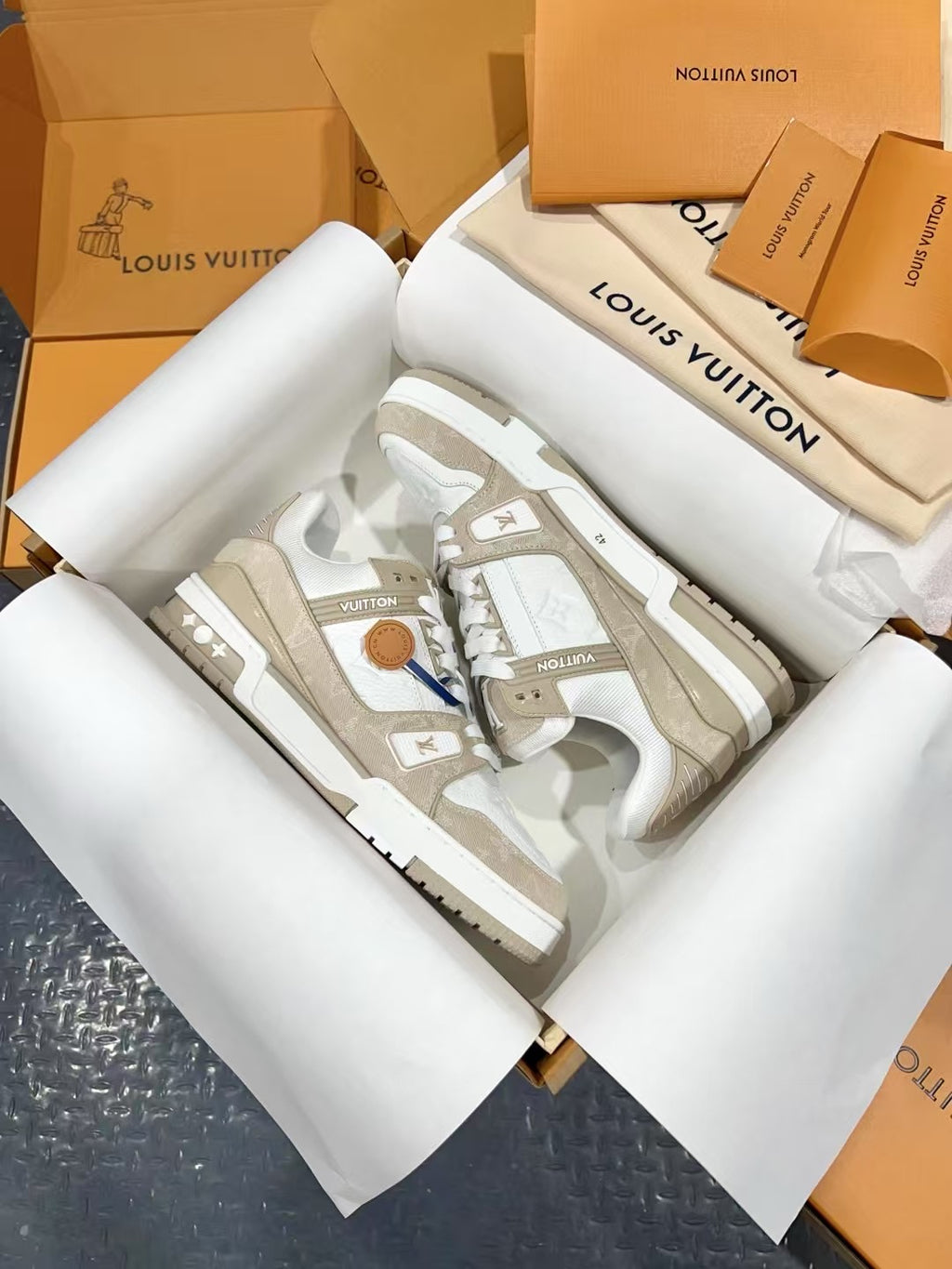 White Louis Vuitton trainer sneakers with monogram side panels and gold-tone lace trim.