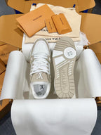 White Louis Vuitton trainer sneakers with LV tongue print and logo sole, front view.