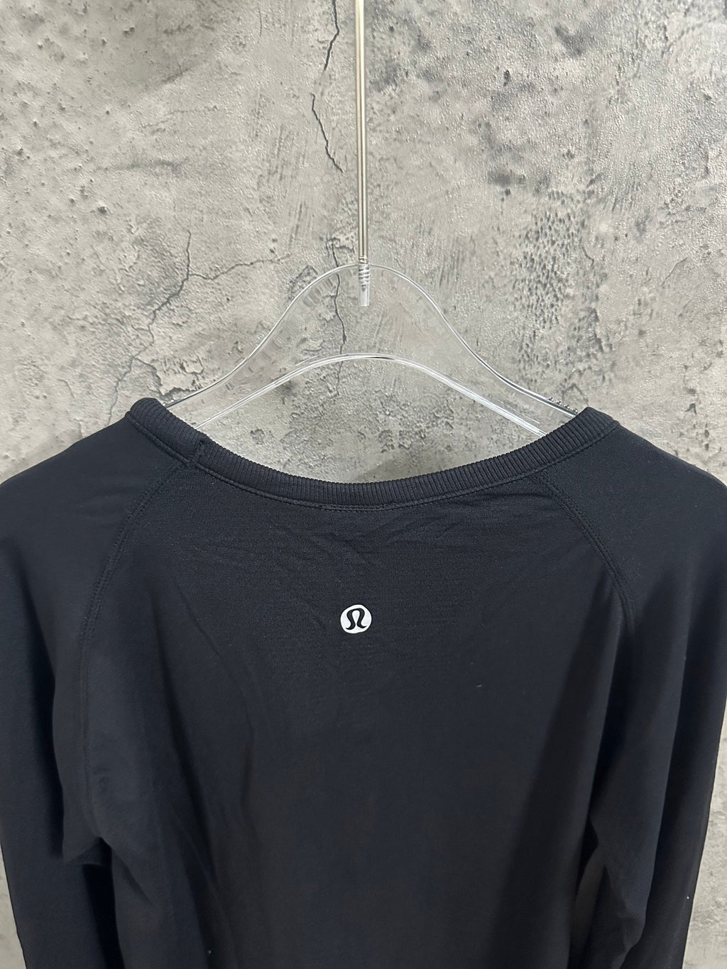 Black crewneck long-sleeve top back view with small logo at upper center