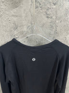 Black crewneck long-sleeve top back view with small logo at upper center