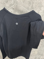 Black long-sleeve top back view with small logo, draped sleeve detail
