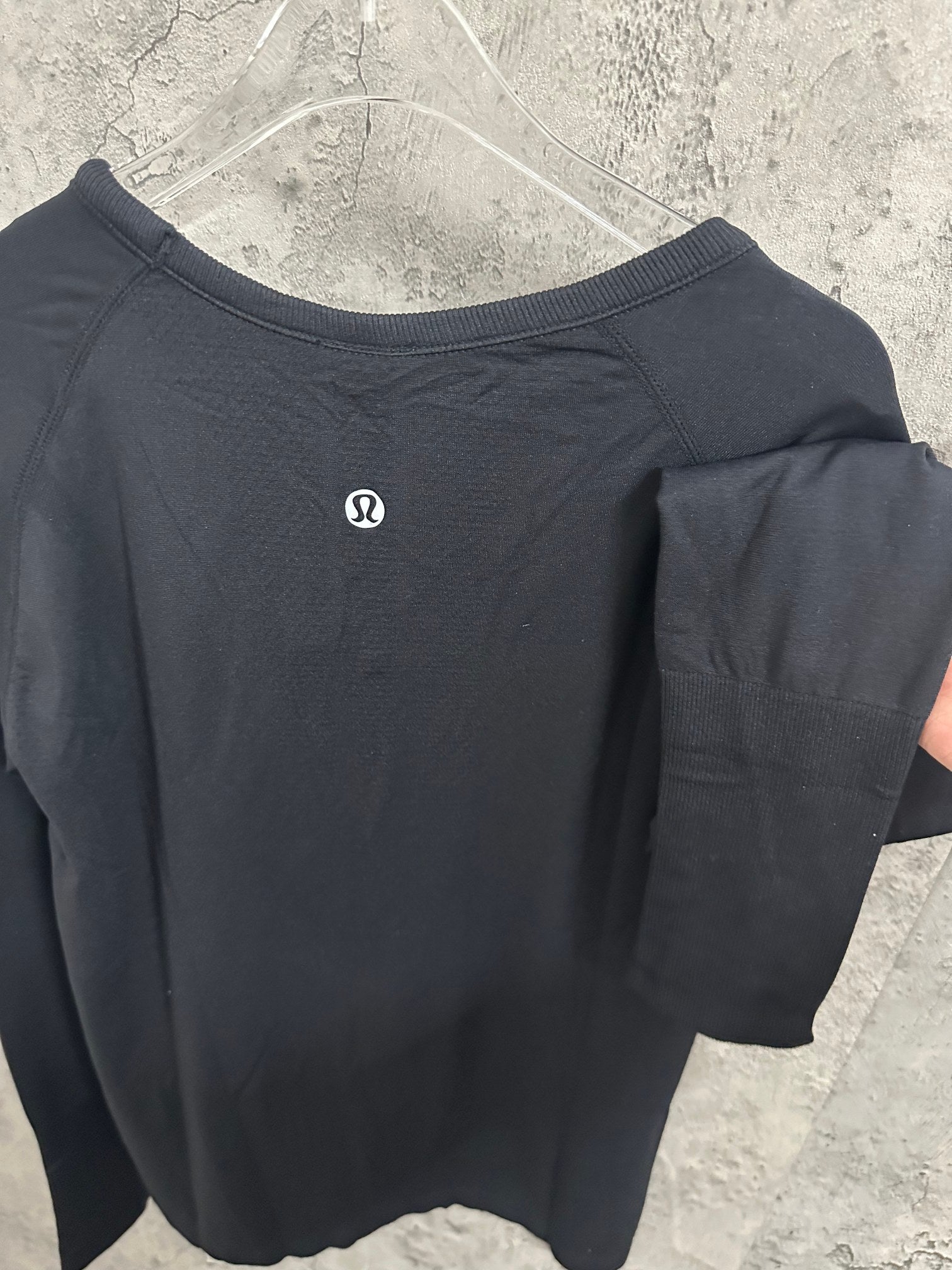 Black long-sleeve top back view with small logo, draped sleeve detail