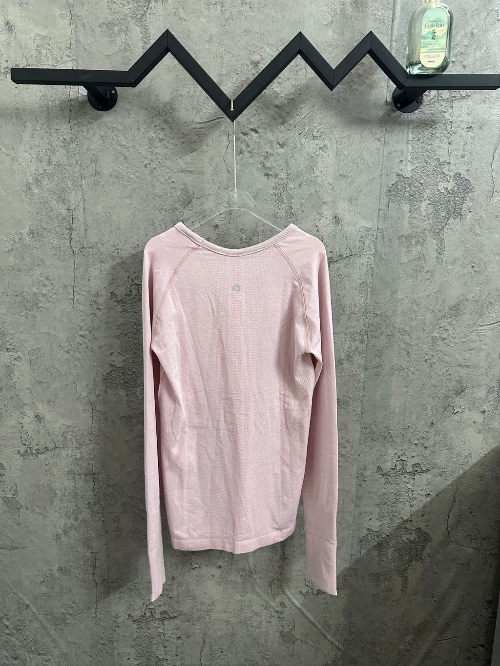 Pink long-sleeve crewneck T-shirt, back view on hanger