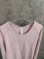 Light pink long-sleeve crewneck top with round neckline and neck label